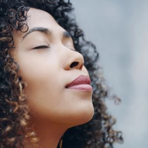 Une femme, yeux fermés, dans le lâcher prise et la sérénité